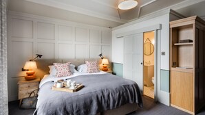A bedroom with a bed, bedside lamps, a tray with items, a wardrobe, and a bathroom door. - Ardgowan Hotel (St. Andrews)