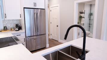 A modern kitchen with stainless steel appliances, a black faucet, and white cabinetry.