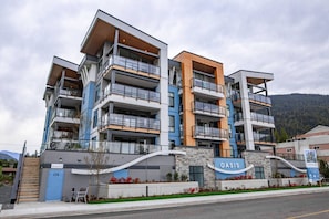 A multi-story building with balconies, a sign reading "OASIS," and a staircase leading to the entrance. - Brand New Penthouse with Lake & Mtn Views (Harrison Hot Springs)