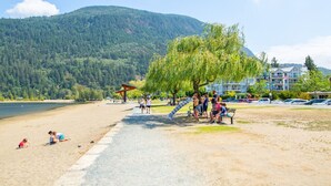 Ein Strand mit einem Spielplatz, einem Weg und einem Gebäude im Hintergrund.