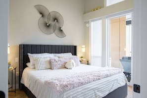 Une chambre moderne avec un grand lit, un élément décoratif mural et une vue sur l’extérieur.