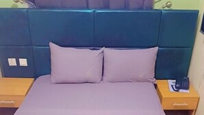 A bed with a headboard, two pillows, and a bedside table with a phone. - Ikad Hotel and Suite Borno Way (Lagos)