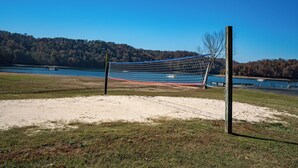 A volleyball net in a sandy area with a lake and forested hills in the background. - Breathtaking Lakeside 2-Bedroom Cabin on Beautiful Dale Hollow Lake #9! (Byrdstown)