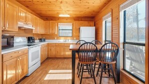 A wooden cabin interior with a kitchen, dining table, and chairs. - 2 Bed Chalet Lakeside with Exceptional View of Dale Hollow Lake  (Byrdstown)