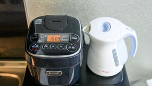 Uma panela elétrica para arroz preta e uma chaleira elétrica branca sobre um eletrodoméstico preto.