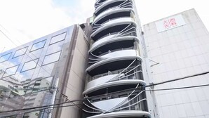 Um edifício de vários andares com fachada curva marcante, entrada visível e uma bicicleta estacionada na frente.