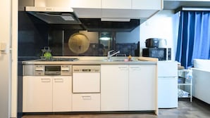 Cozinha compacta equipada com lava-louças, fogão, micro-ondas e um frigorífico pequeno.