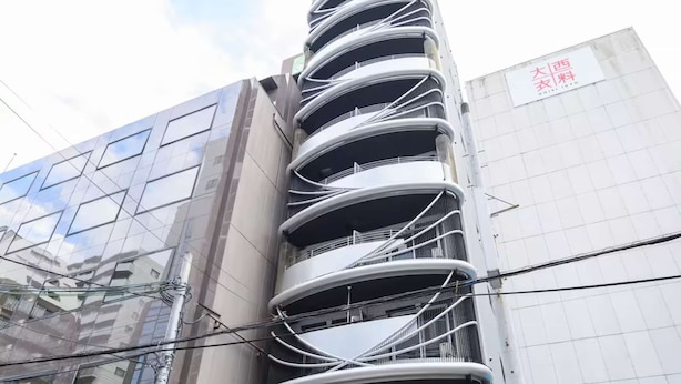 Um edifício de vários andares com fachada curva marcante, entrada visível e uma bicicleta estacionada na frente.