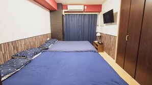 Une chambre d’hôtel avec deux lits, une armoire, un téléviseur et un appareil de climatisation.