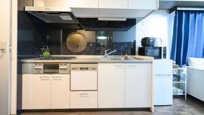 Una cocina compacta con lavavajillas, estufa, microondas y un refrigerador pequeño.