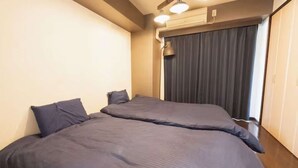 Una habitación con dos camas, una ventana con cortinas y un equipo de aire acondicionado.