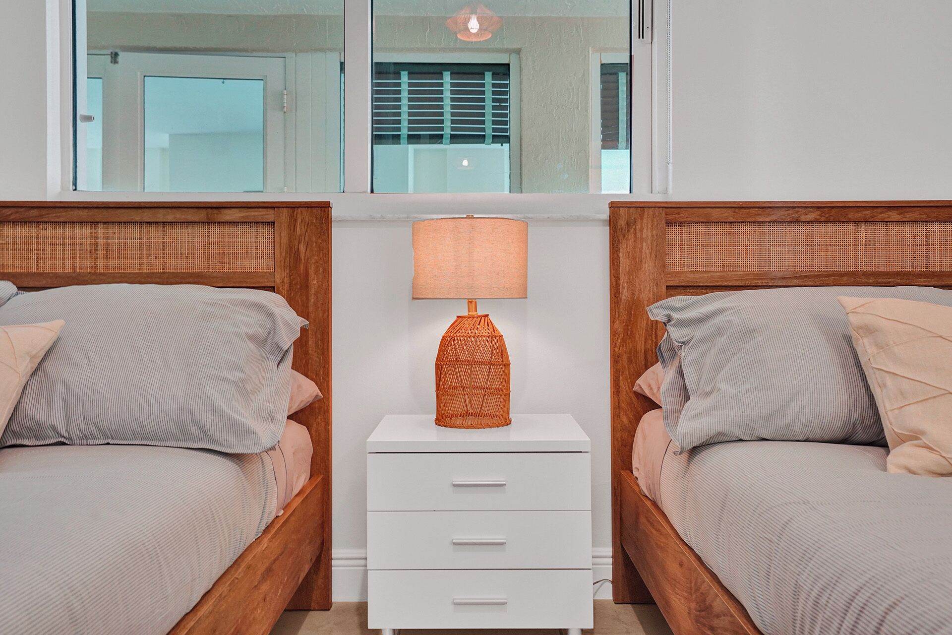 Una camera da letto con due letti, un comodino con lampada e uno specchio sopra i letti.