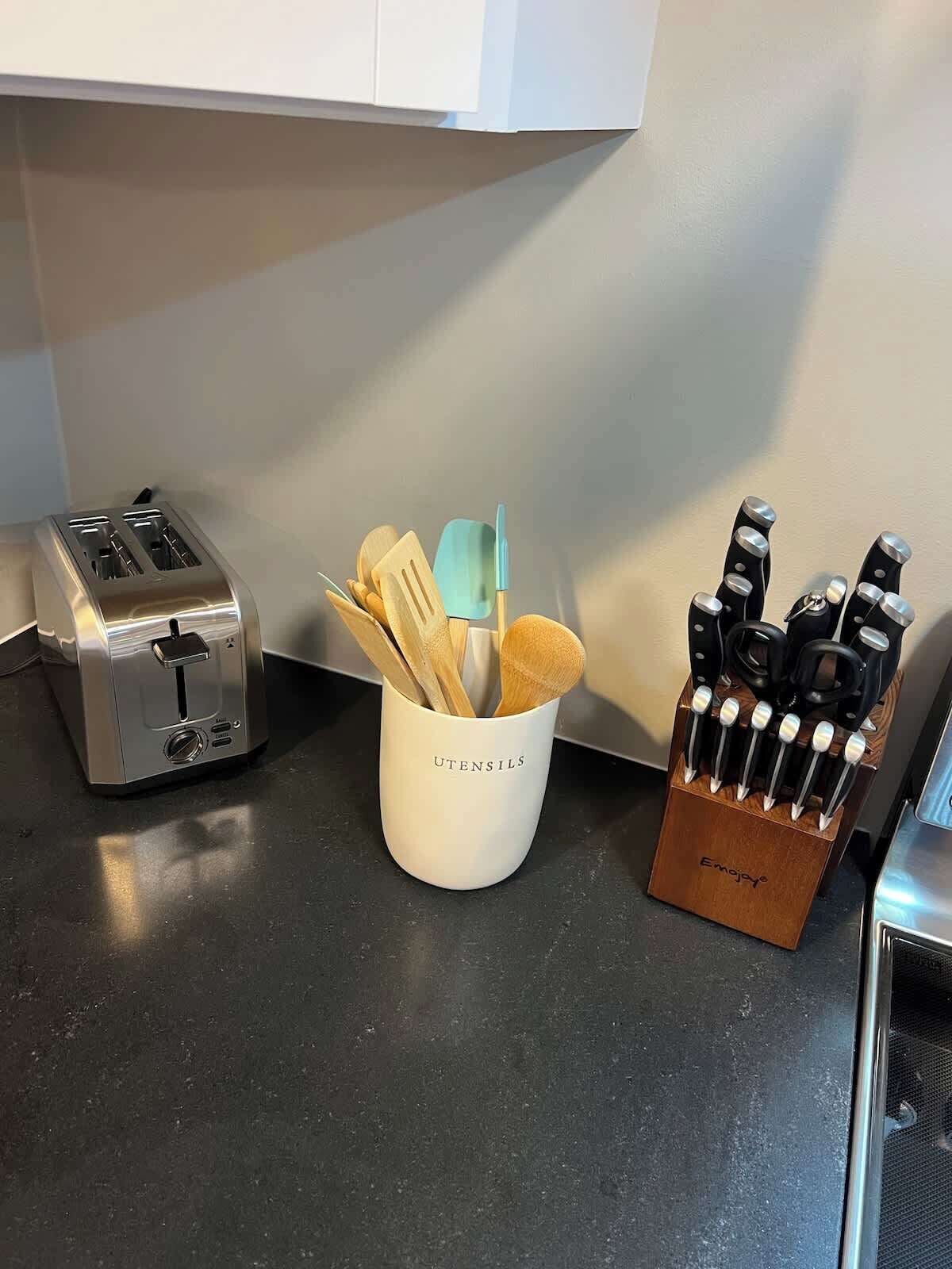 A kitchen counter with a toaster, a utensil holder, and a knife block.