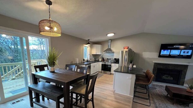 Una cocina moderna con comedor, chimenea y televisor montado en la pared.