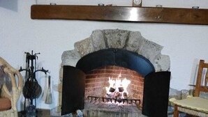 A fireplace with a stone arch, a tiled floor, and a wooden chair.