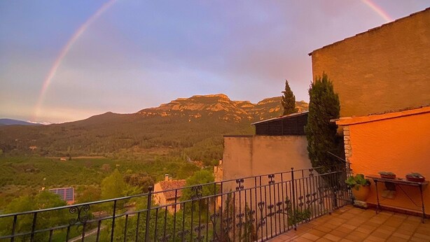 A balcony with a view of a mountain range and a rainbow.