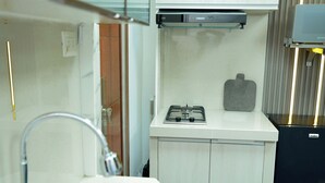 Una cocina moderna con un lavamanos de acero inoxidable, una estufa a gas y un microondas.