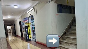 Un pasillo con una escalera, una señal con flecha direccional y una puerta que indica 'MARCELINO RELOJAS'.