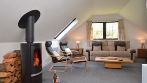 A cozy living room with a wood-burning stove, a sofa, two armchairs, and a coffee table. - Heronlea Cottage -  Picturesque Scottish setting, 4 guests, pet friendly,  (Dunoon)