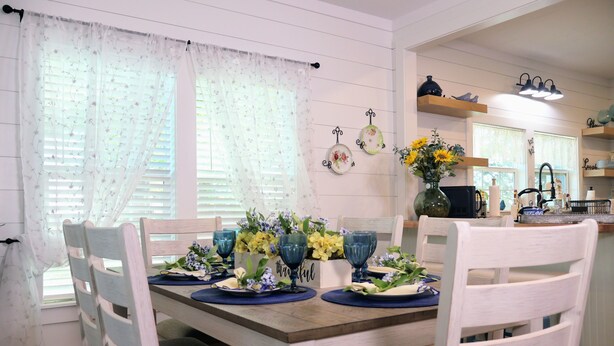 A dining area with a wooden table set for four, surrounded by white chairs. - Barby Haus (Bellville)