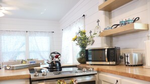 A kitchen with white cabinets, a microwave, a kettle, and a toaster. - Barby Haus (Bellville)