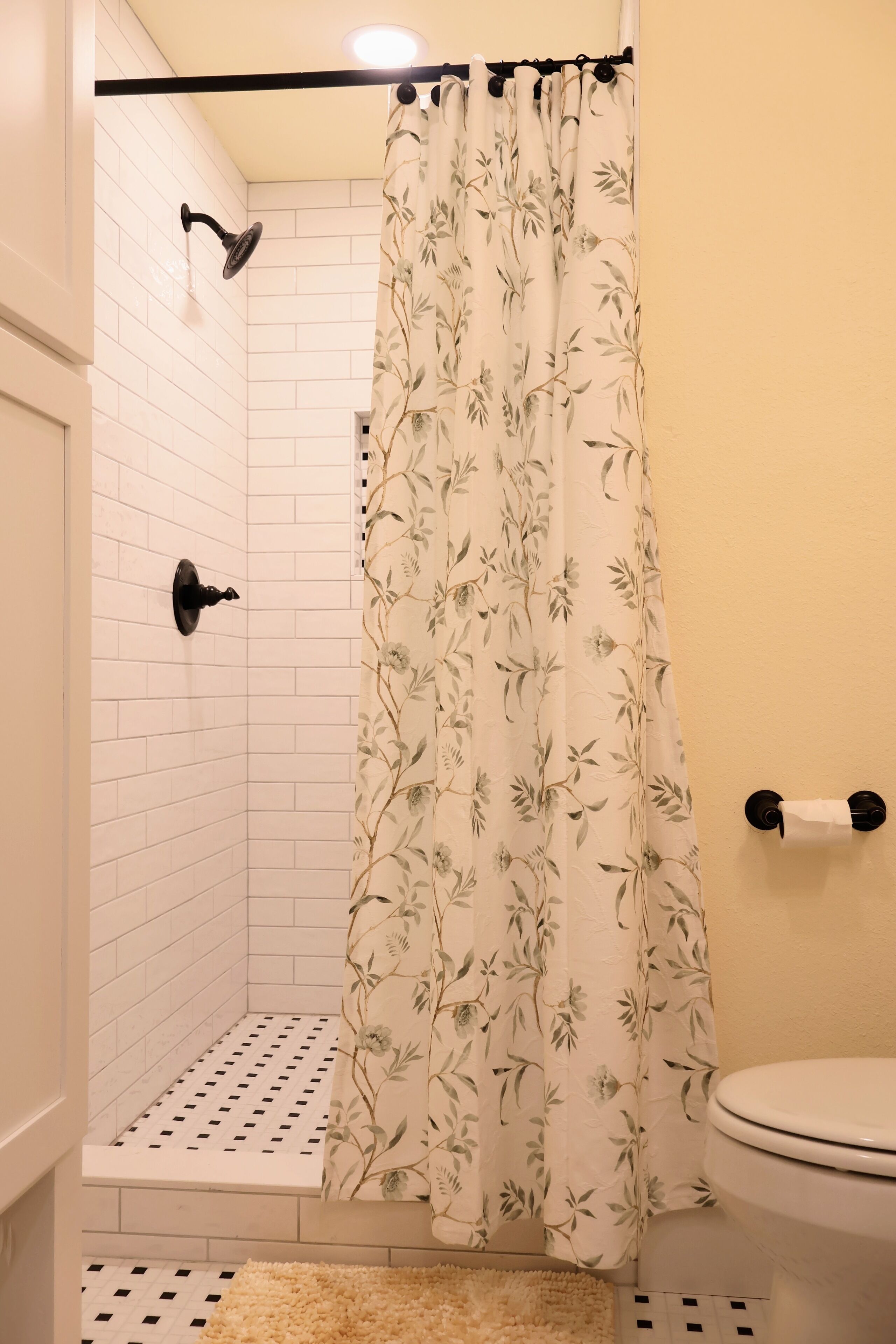 A bathroom with a shower, toilet, and a floral shower curtain.