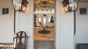 Un vestíbulo con suelo de madera, un candelabro, dos faroles en la pared y una alfombra estampada.