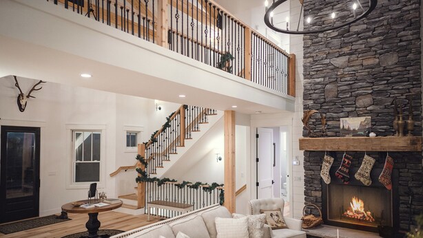 Un amplio salón con chimenea, una escalera con barandillas de madera y una zona de estar acogedora.