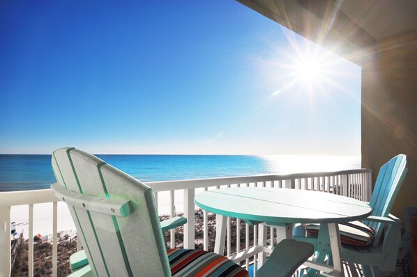 A balcony with a view of the ocean, a table, and two chairs. - Waters Edge 613 • Top Floor Beach Gem, Perfect Views, Luxury Condo, Pool, Covered Parking (Fort Walton Beach)