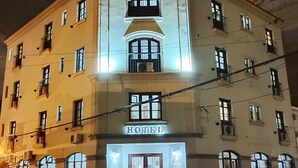 Un hotel de estilo arquitectónico clásico, con una entrada central que tiene un doble acceso y un letrero encima.