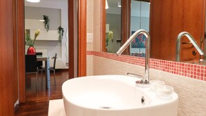 A bathroom with a white sink, chrome faucet, and a red-tiled backsplash.