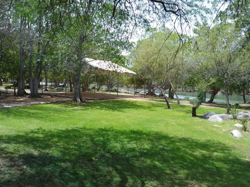 Un parc avec un kiosque, des arbres et un étang.
