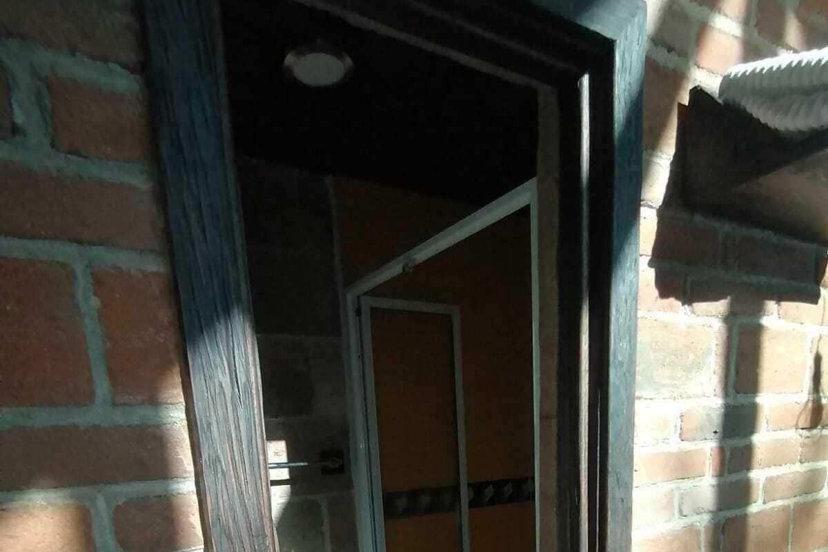 Una puerta que da a una habitación con piso de baldosas y pared de ladrillo.
