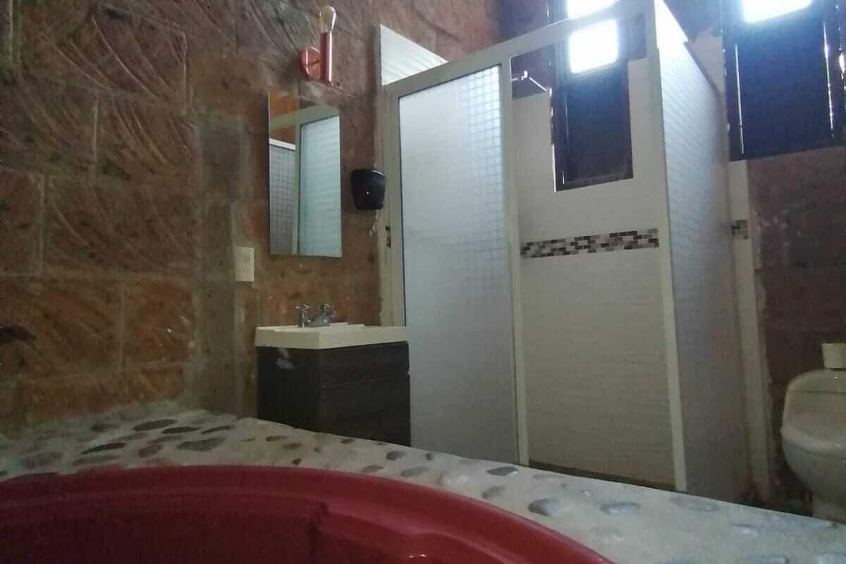 Un baño con una bañera roja, un lavabo, un espejo y un inodoro.