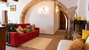 A cozy living room with a red sofa, a patterned rug, and a stone fireplace.