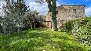 A stone building with a garden, a tree, and a patio area.