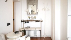 A bathroom with a white sink, a mirror, a radiator, and a shelf with decorative items. - Zaffiro Bianco Central home (San Gimignano)