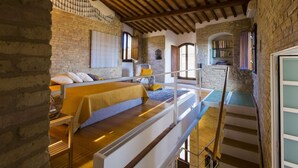 Une chambre à coucher avec un lit, une chaise en bois, un escalier et une bibliothèque.