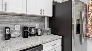 Una cocina con armarios blancos, un refrigerador de acero inoxidable, una cafetera y un tostador.