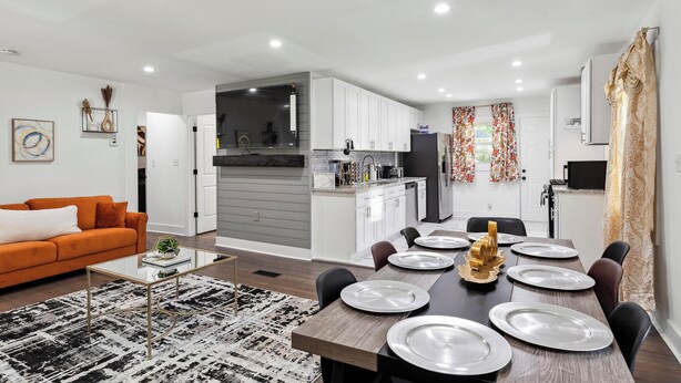 Una sala moderna con sofá, mesa de centro y comedor con sillas y platos.