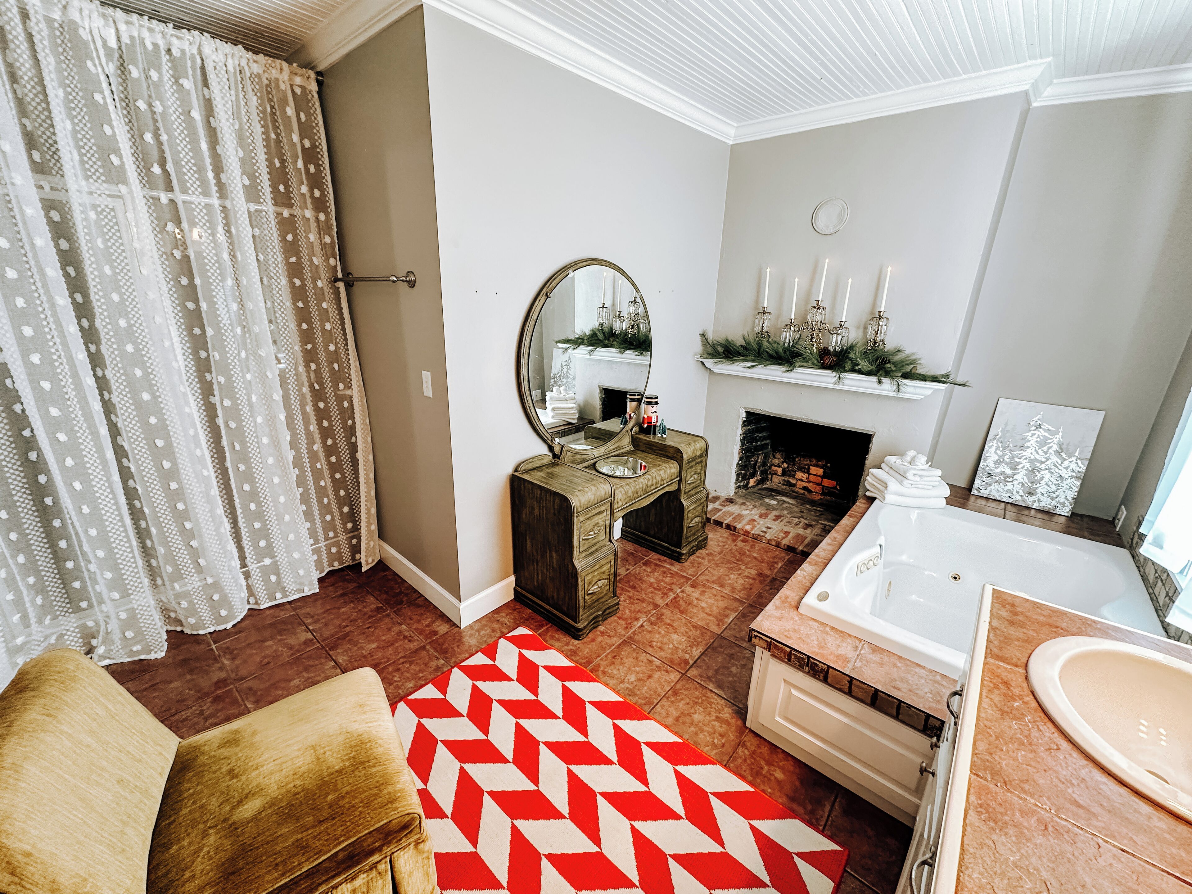 A bathroom with a bathtub, a sink, a mirror, and a fireplace.