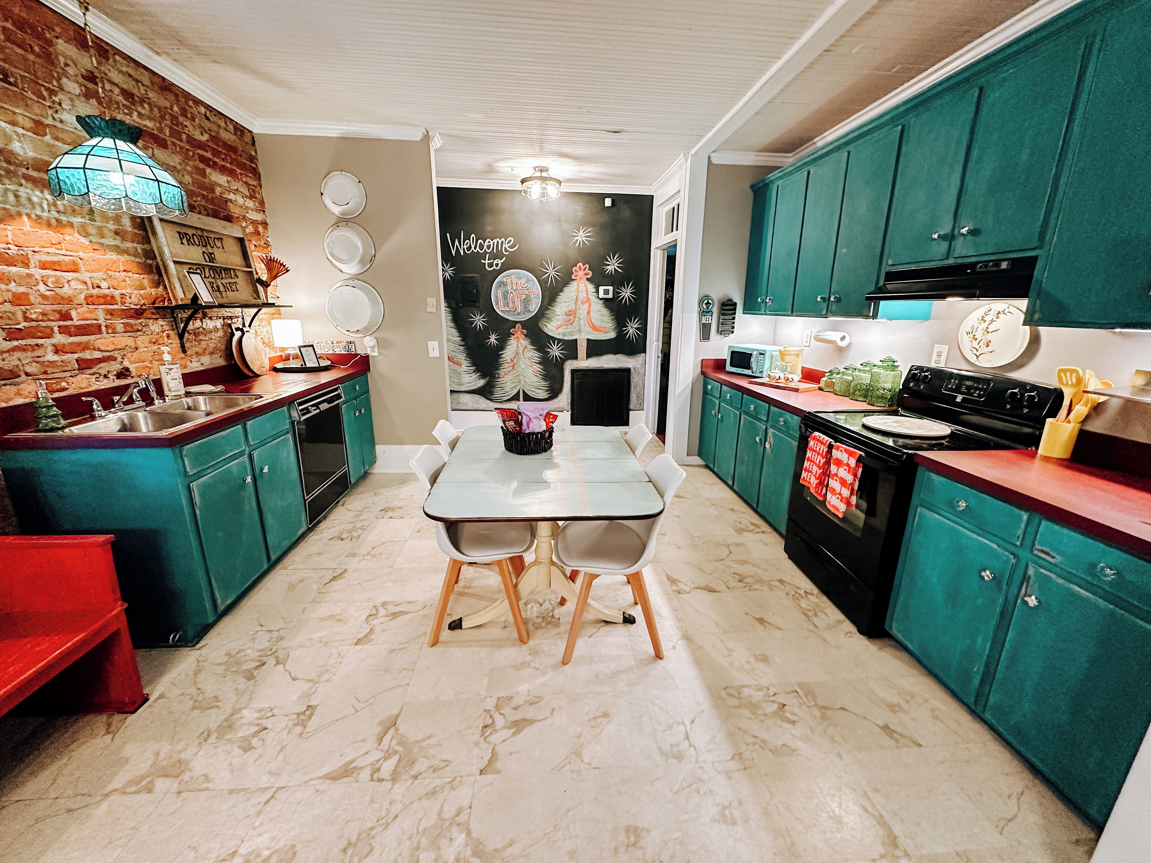 Une cuisine avec des meubles de couleur turquoise, un îlot central et une table à manger.