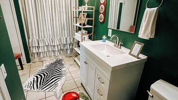 Een badkamer met een zebra vloerkleed, een witte wastafel, een toilet en een groene wand.