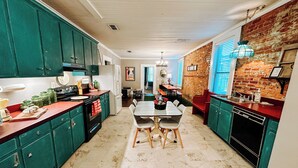 Una cocina con armarios color turquesa, piso de mármol y comedor con mesa y sillas.