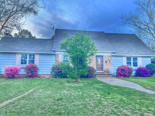 A two-story house with a brick facade, a blue roof, and a front door with a small porch. - Spacious Home n Garden (Spanish Fort)