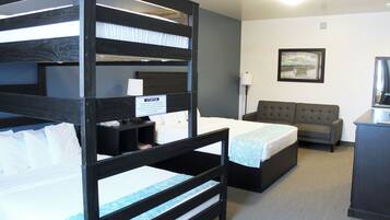 A hotel room with bunk beds, a sofa, a desk, and a framed picture on the wall.