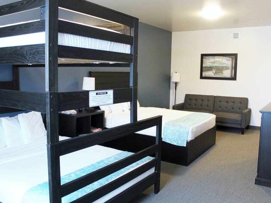 A hotel room with bunk beds, a sofa, a desk, and a framed picture on the wall.