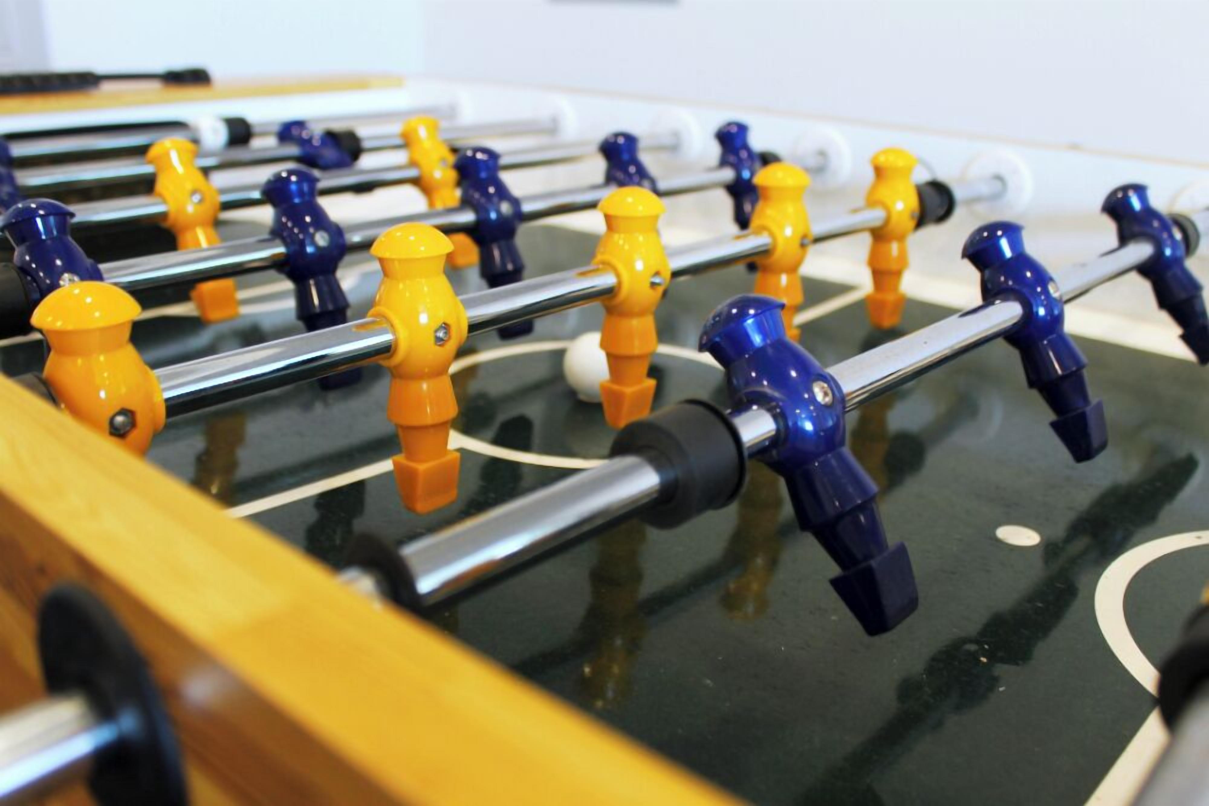 A foosball table with yellow and blue player figures.