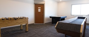 Una habitación con mesa de futbolín, mesa de billar y una puerta con un letrero.