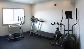 Un gimnasio con cinta de correr, elíptica y bicicleta estática.